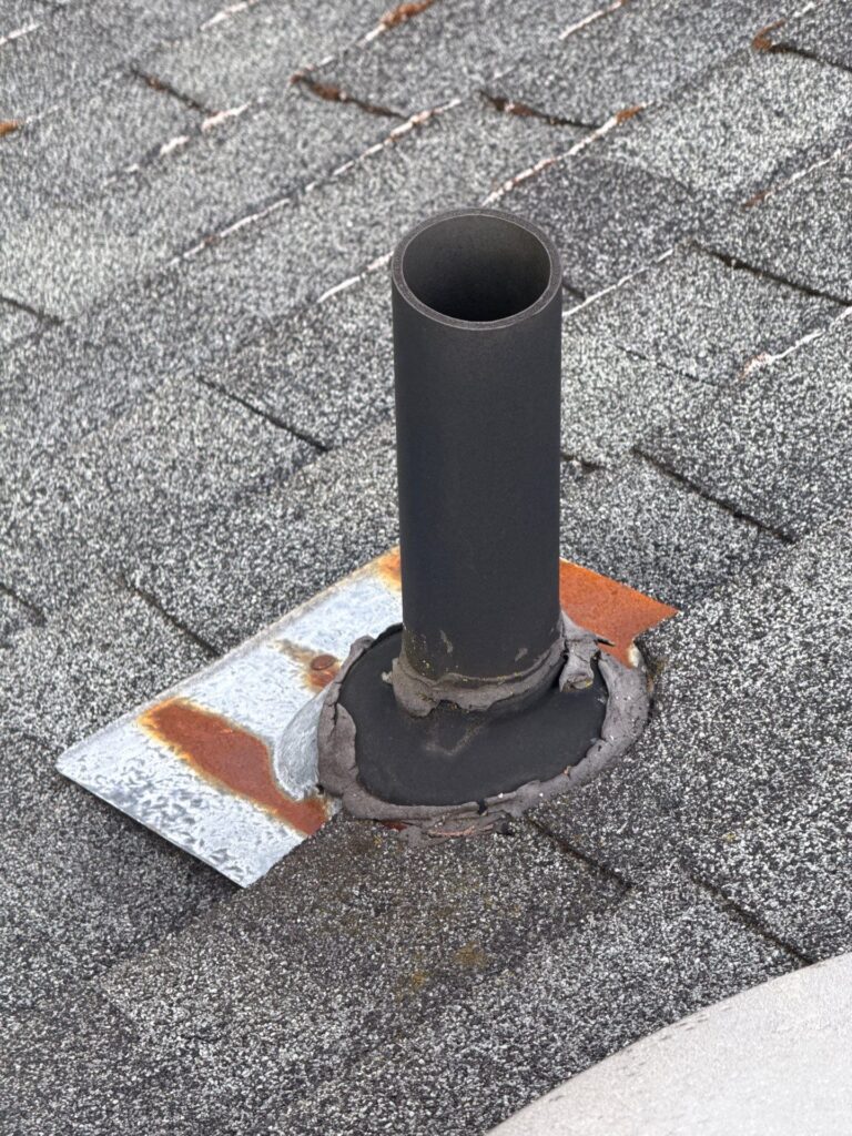 Close-up of a cracked synthetic rubber pipe boot around a roof vent, showing how aging materials allow water to seep into the interior of the home during heavy rain.